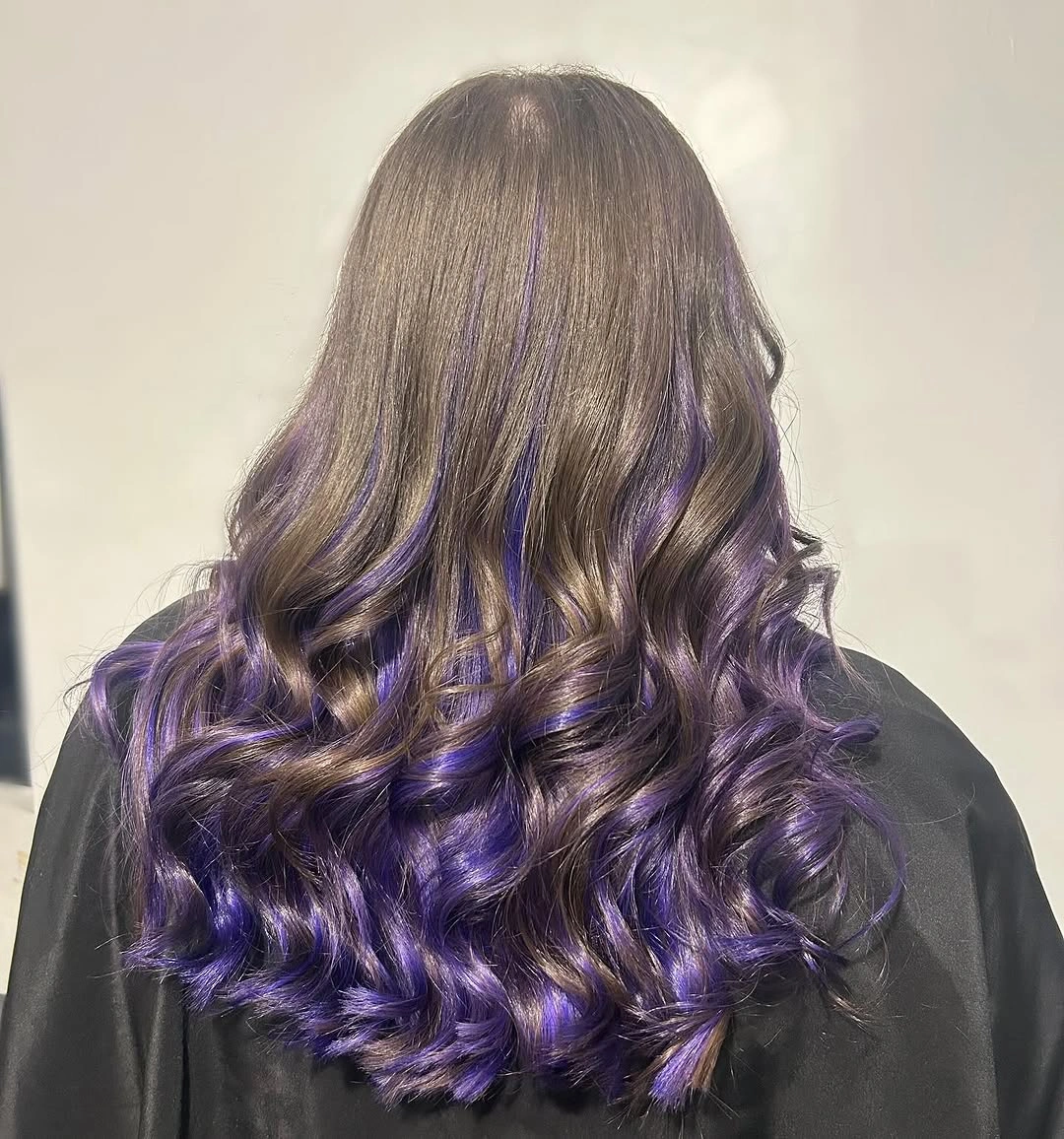Dark curled hair with vivid violet sections through lower lengths