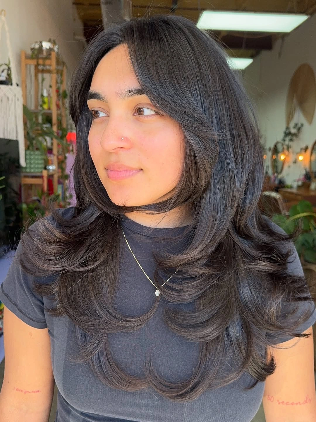Dark center-parted layered hair with face-framing curved pieces