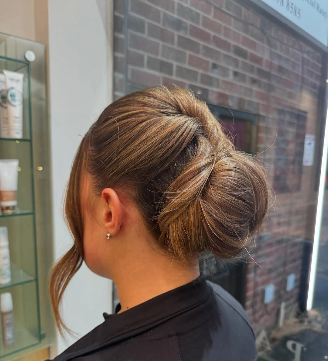 Rounded low bun with diagonal wrap and loose front strand