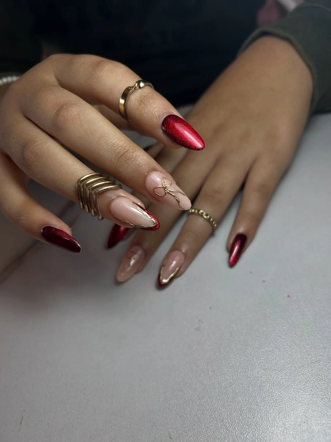 Long almond nails with reflective red and fine gold-toned details