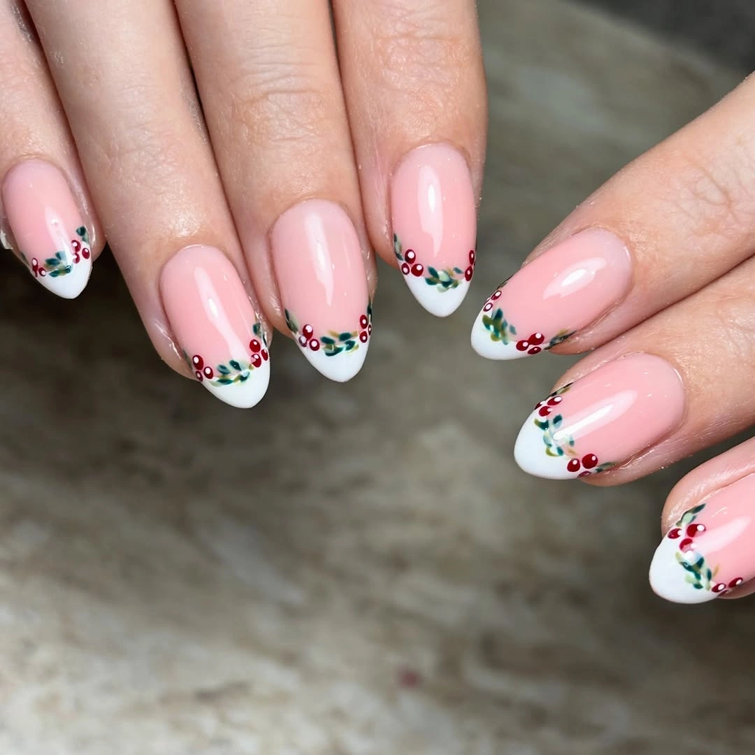 Pink almond nails with white tips, red berries, and green leaves