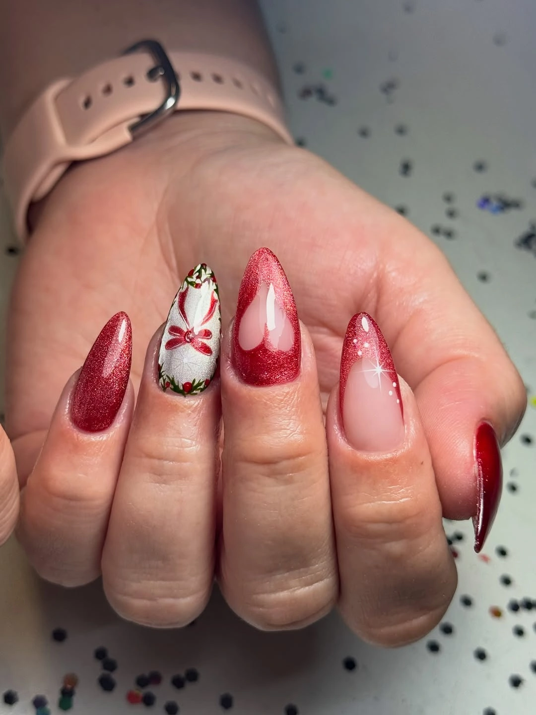 Long red shimmer nails with bow and nude negative-space accents