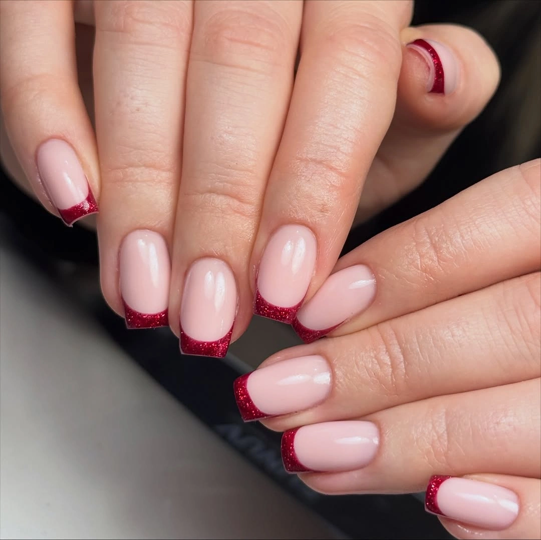 Square pale pink nails with consistent deep red glitter French tips