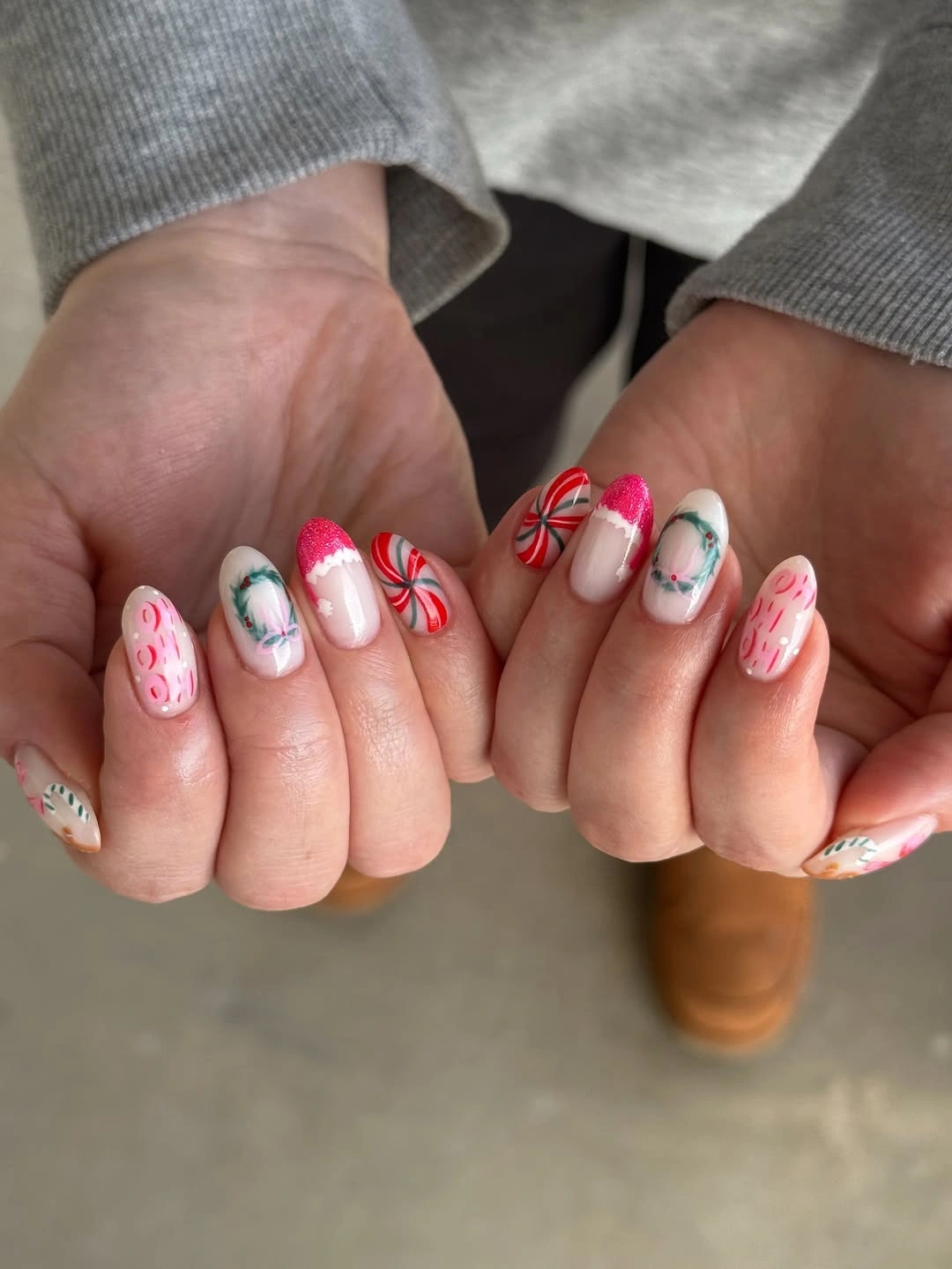Rounded pink and white nails with peppermint swirls and green wreath details