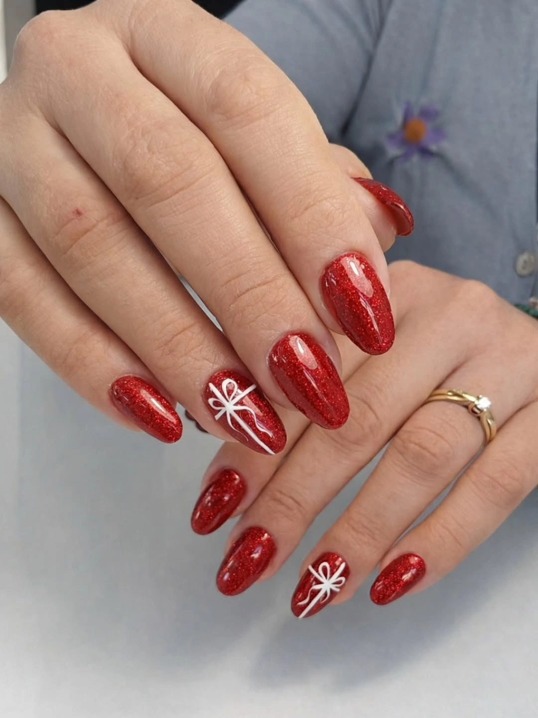 Red almond nails with sparkle and white gift-bow linework