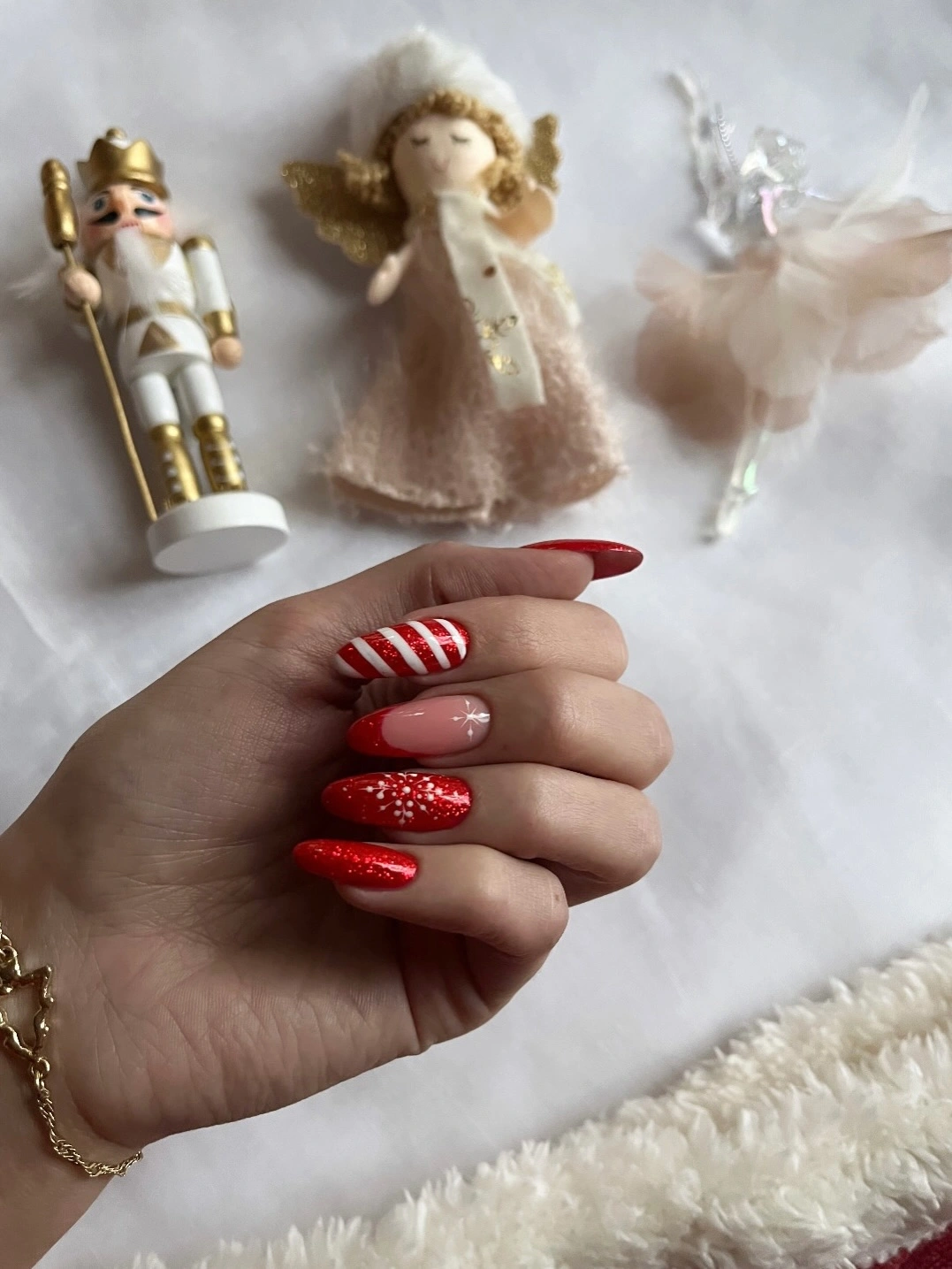 Red almond nails with candy stripes, sparkle, and pale pink accent