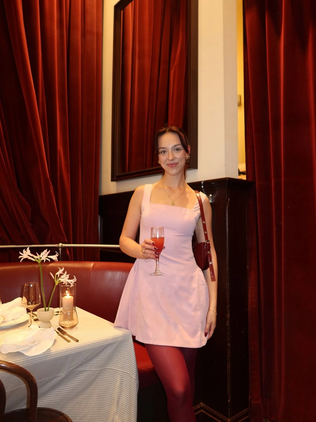Pale pink mini dress with deep red tights and shoulder bag