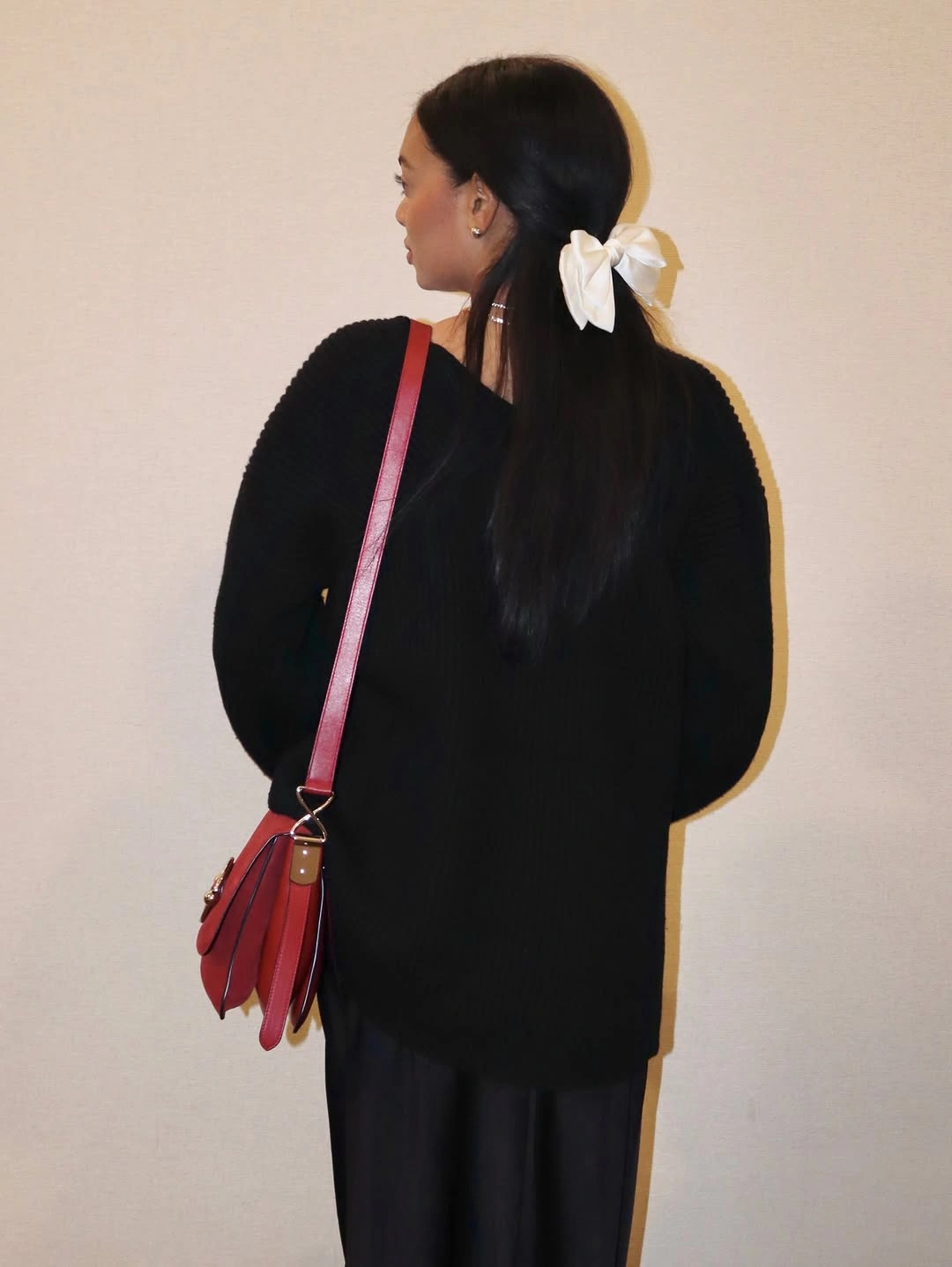 Black sweater and trousers with red bag and white bow