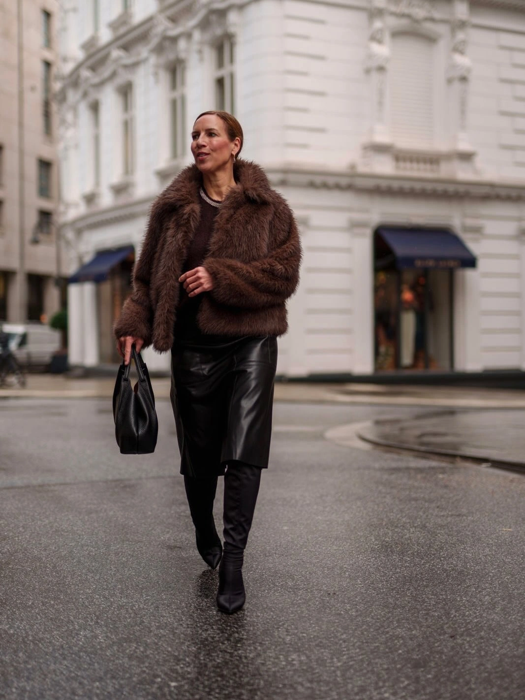 Brown shaggy jacket with black Bermuda shorts and tall boots