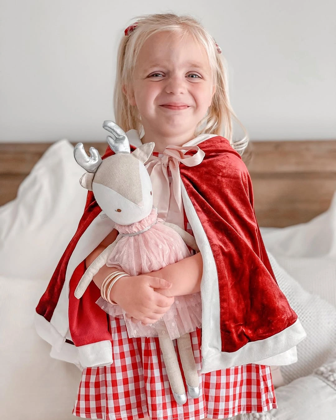 Child wears red cape over red and white checked dress