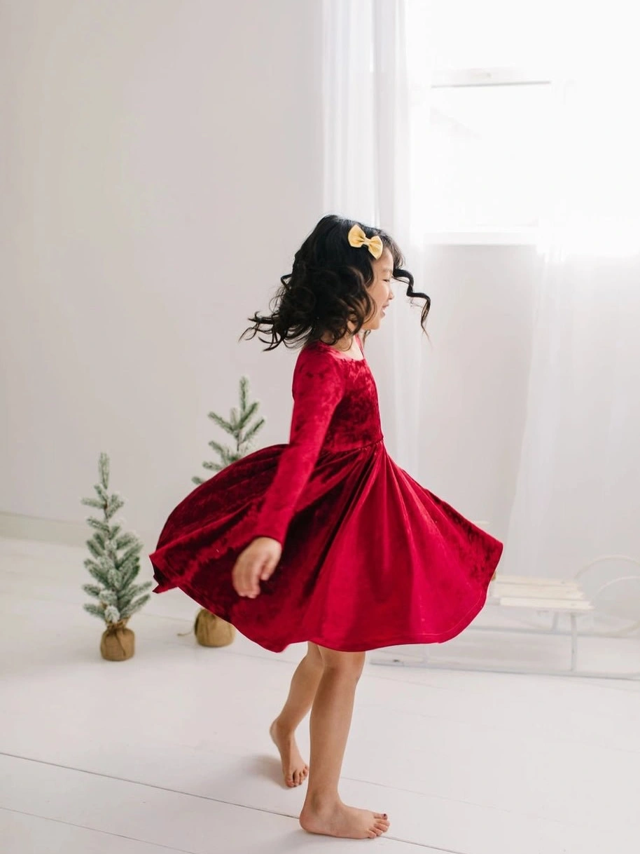 Child wears deep red dress with full moving skirt