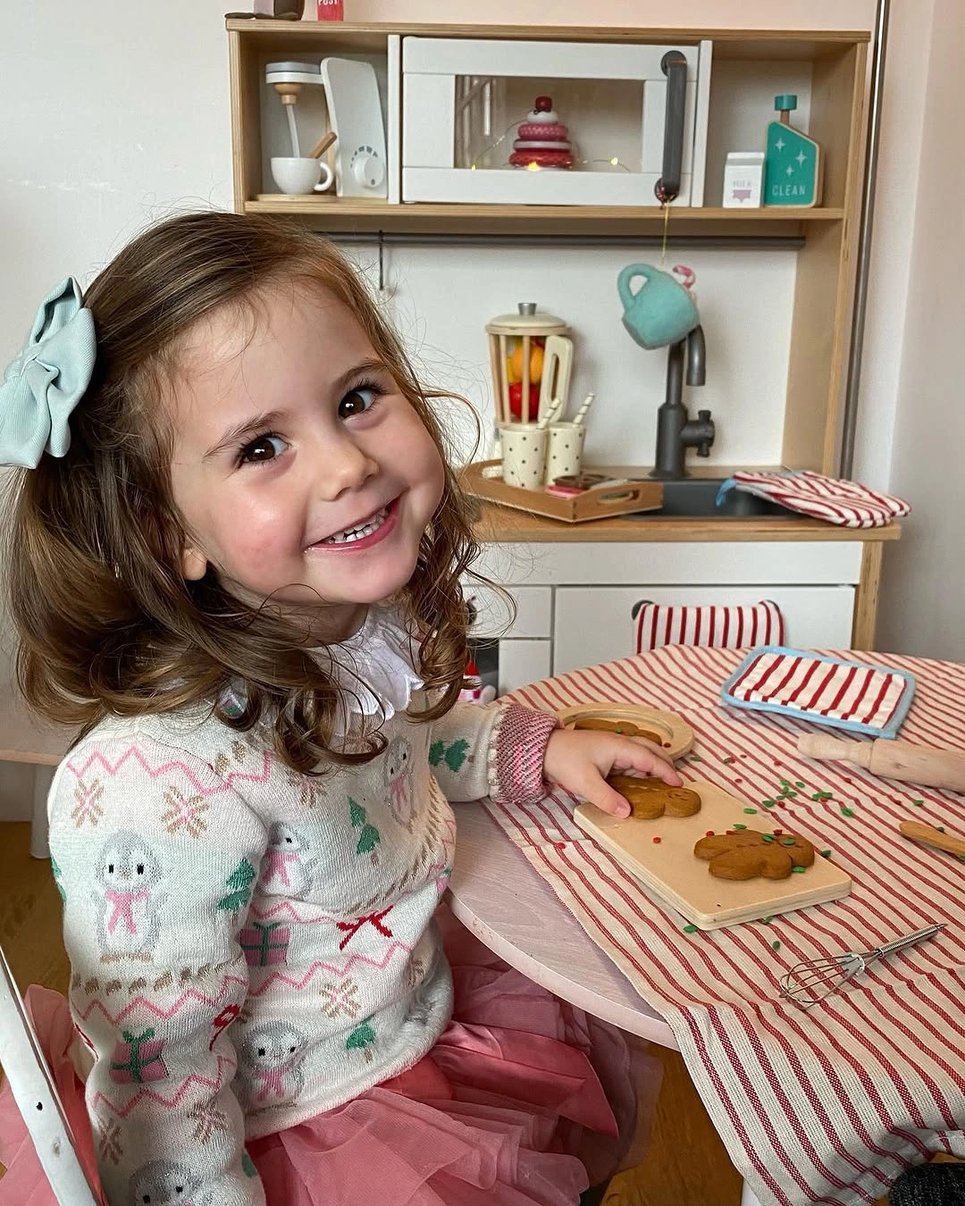 Child wears pale motif sweater with layered pink skirt