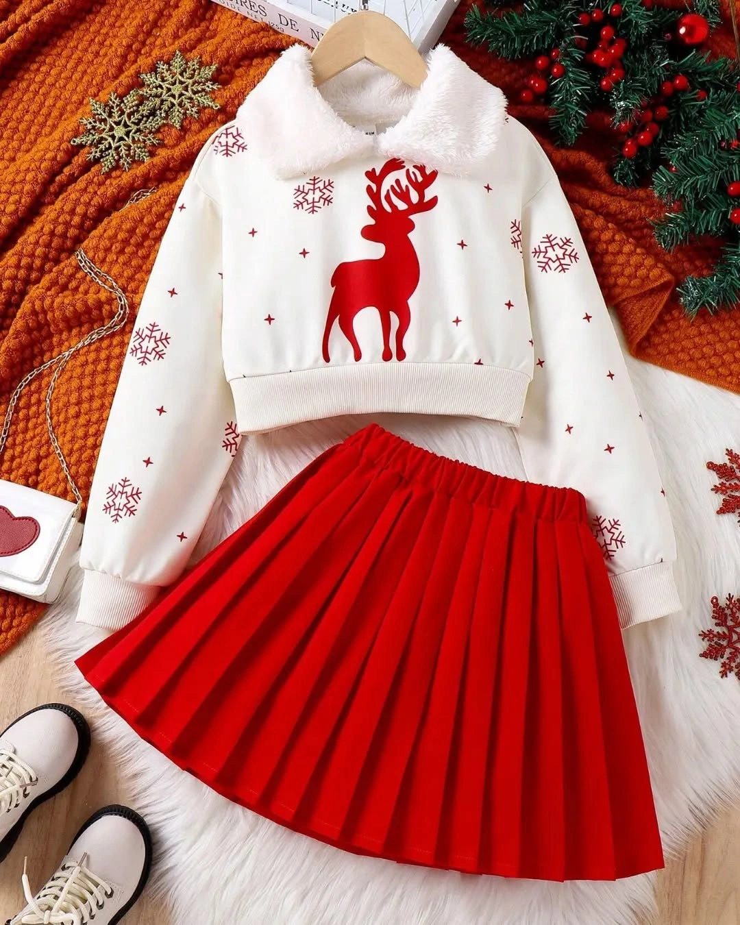 White reindeer hoodie lies beside bright red pleated skirt