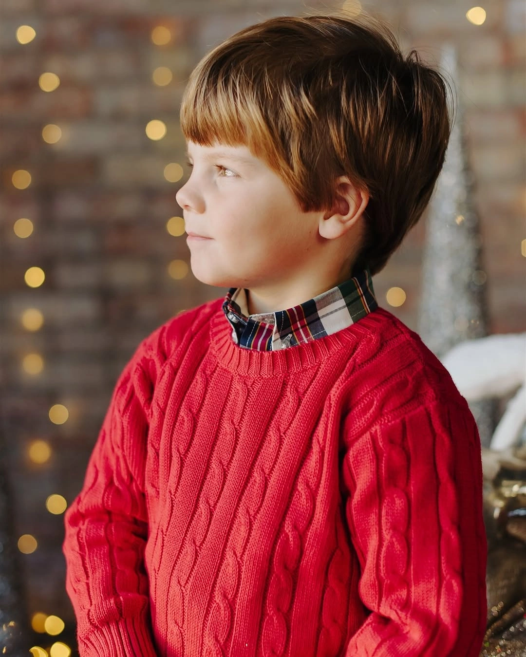 Bright red textured sweater layered over plaid collared shirt