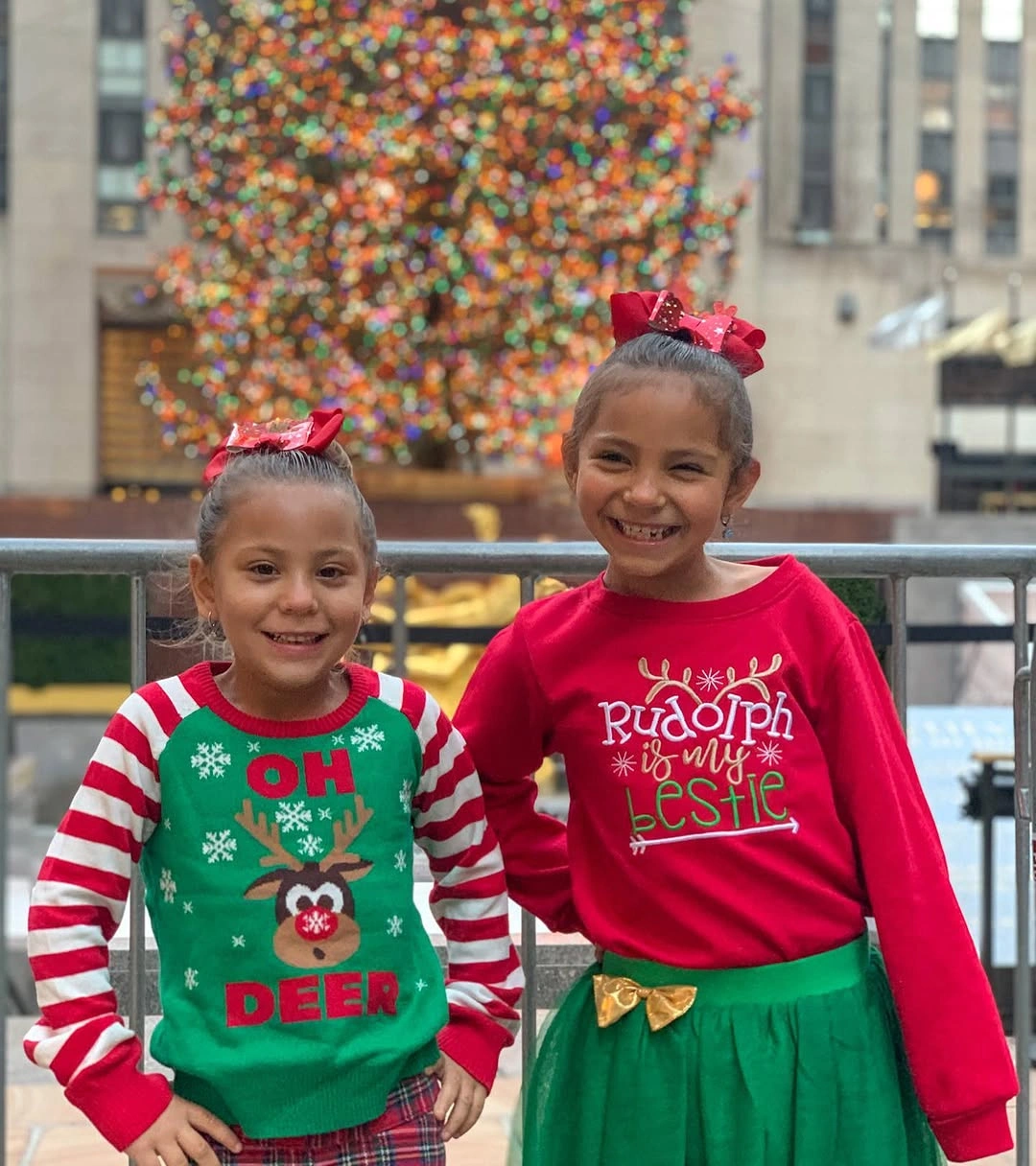 Two children wear graphic red and green Christmas outfits