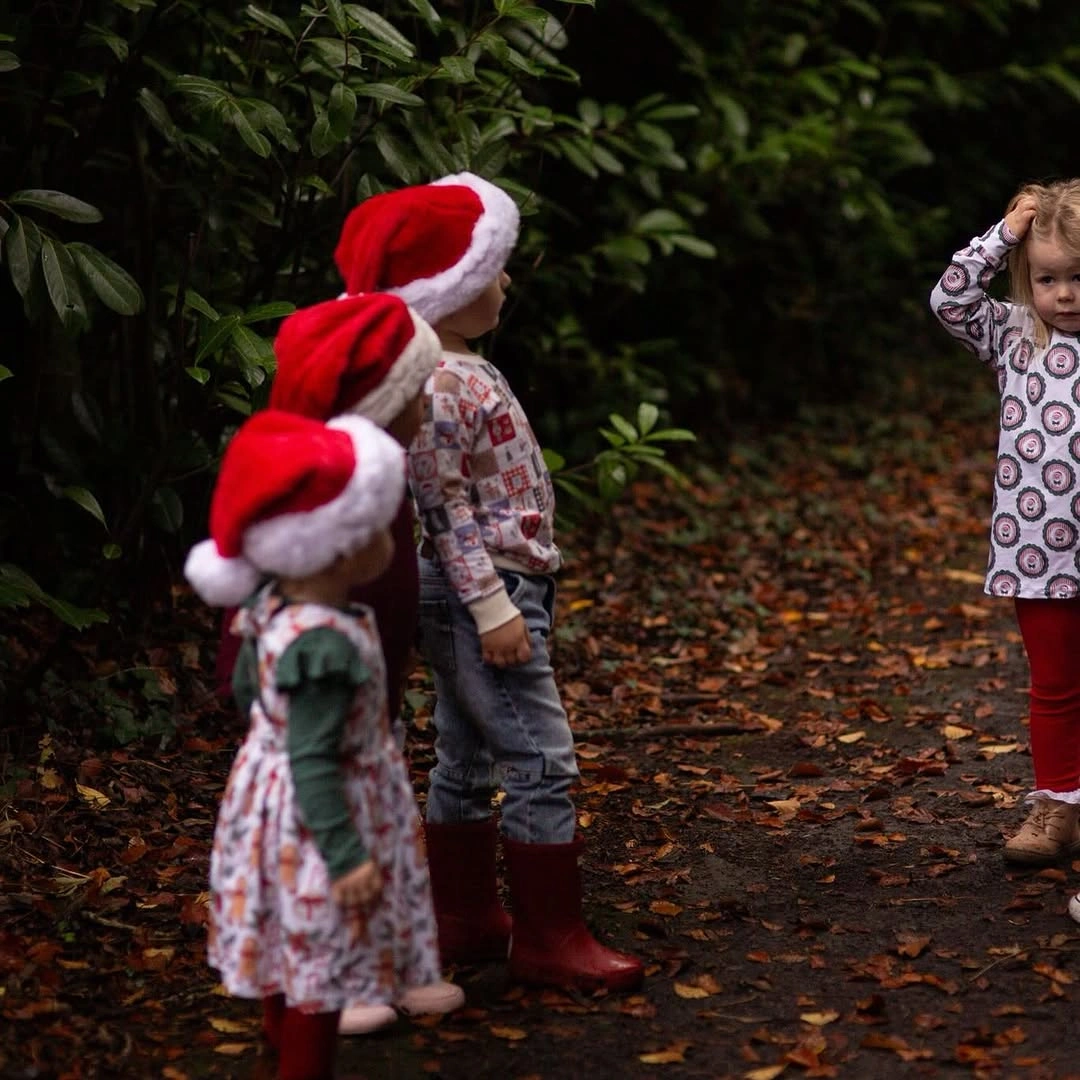 Three children wear distinct outfits with repeated red accents
