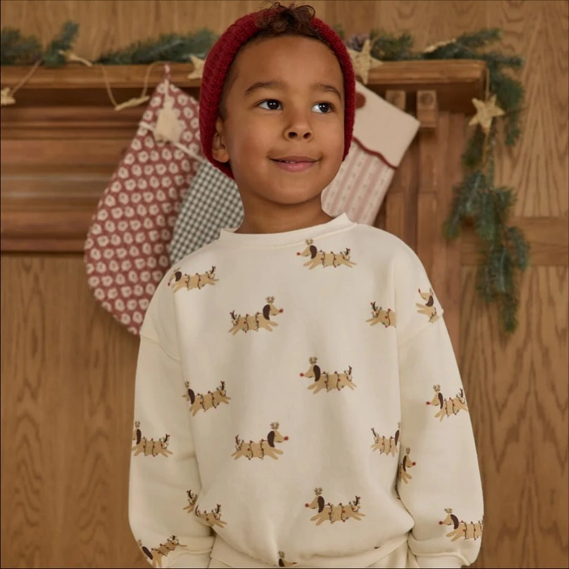 Child wears cream reindeer sweatshirt with red headband