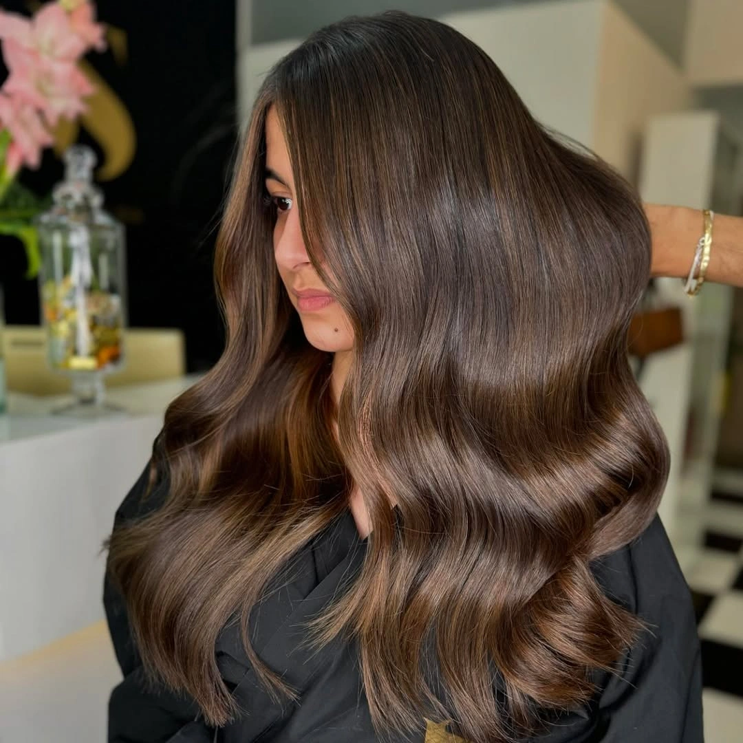 Glossy brunette waves with caramel brightness through the curves