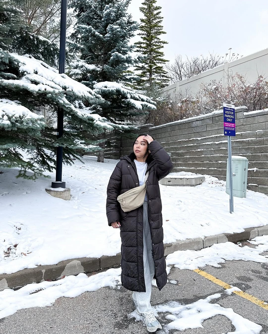 long black puffer, white joggers, black bag and sunglasses