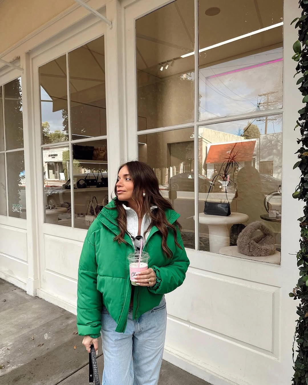 green puffer over a white layer with blue jeans and coffee