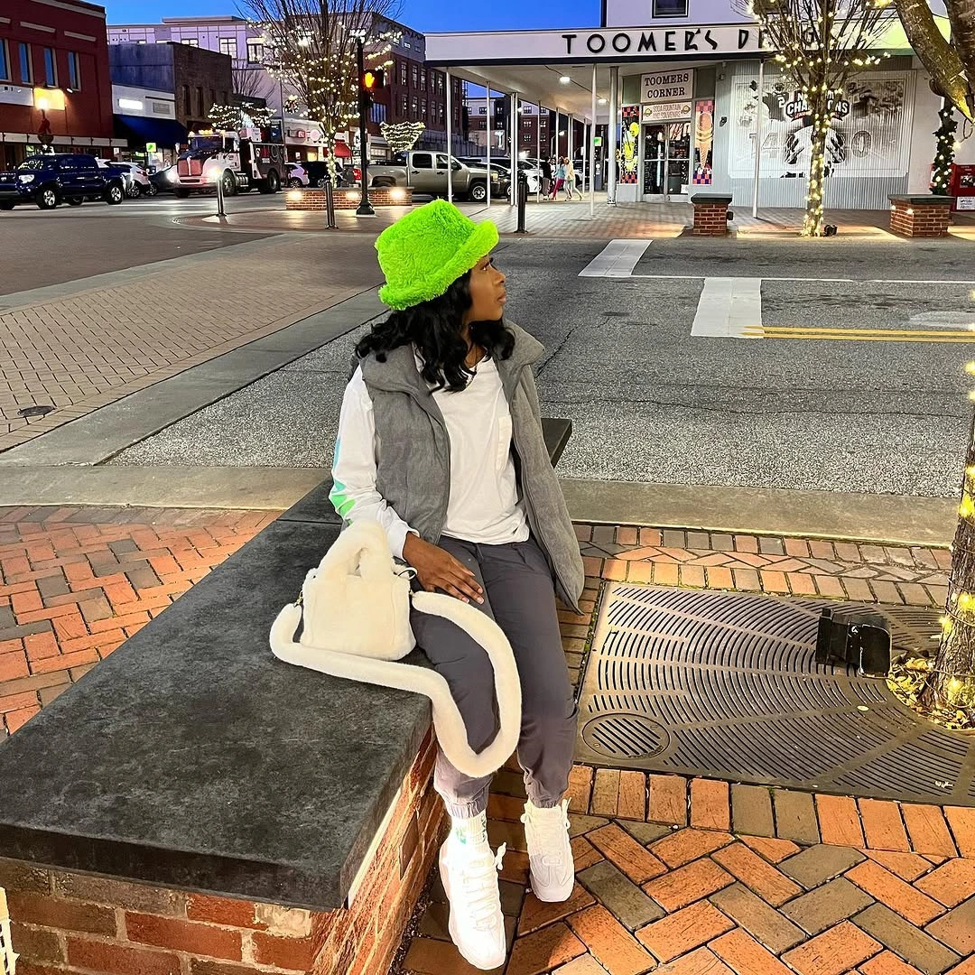cream shearling jacket, neon green beanie, black pants and pale boots