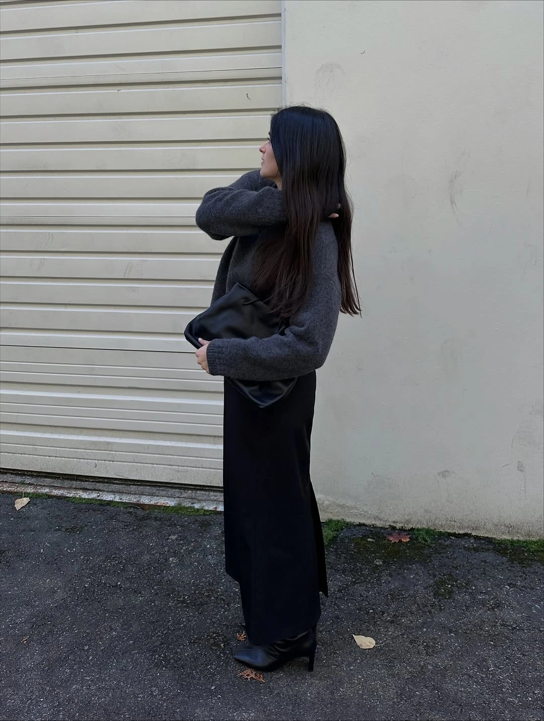 Gray sweater with long black skirt and black bag outdoors