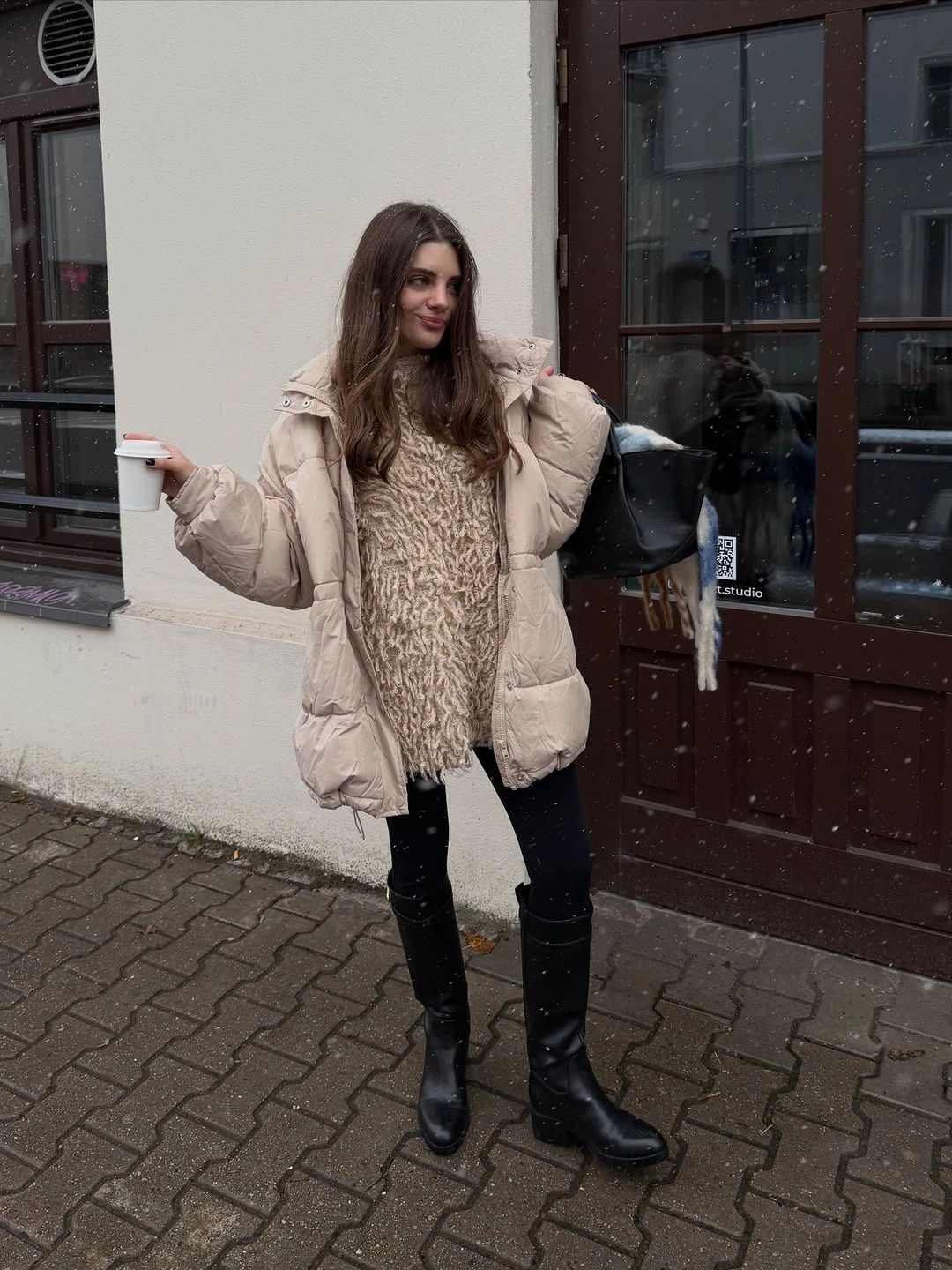 Beige puffer jacket with cream textured sweater, black trousers, and tall boots