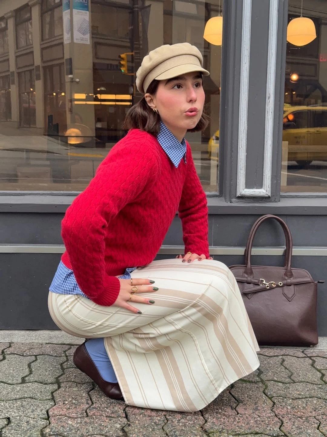 Red sweater over a blue-and-white shirt with a long cream plaid skirt