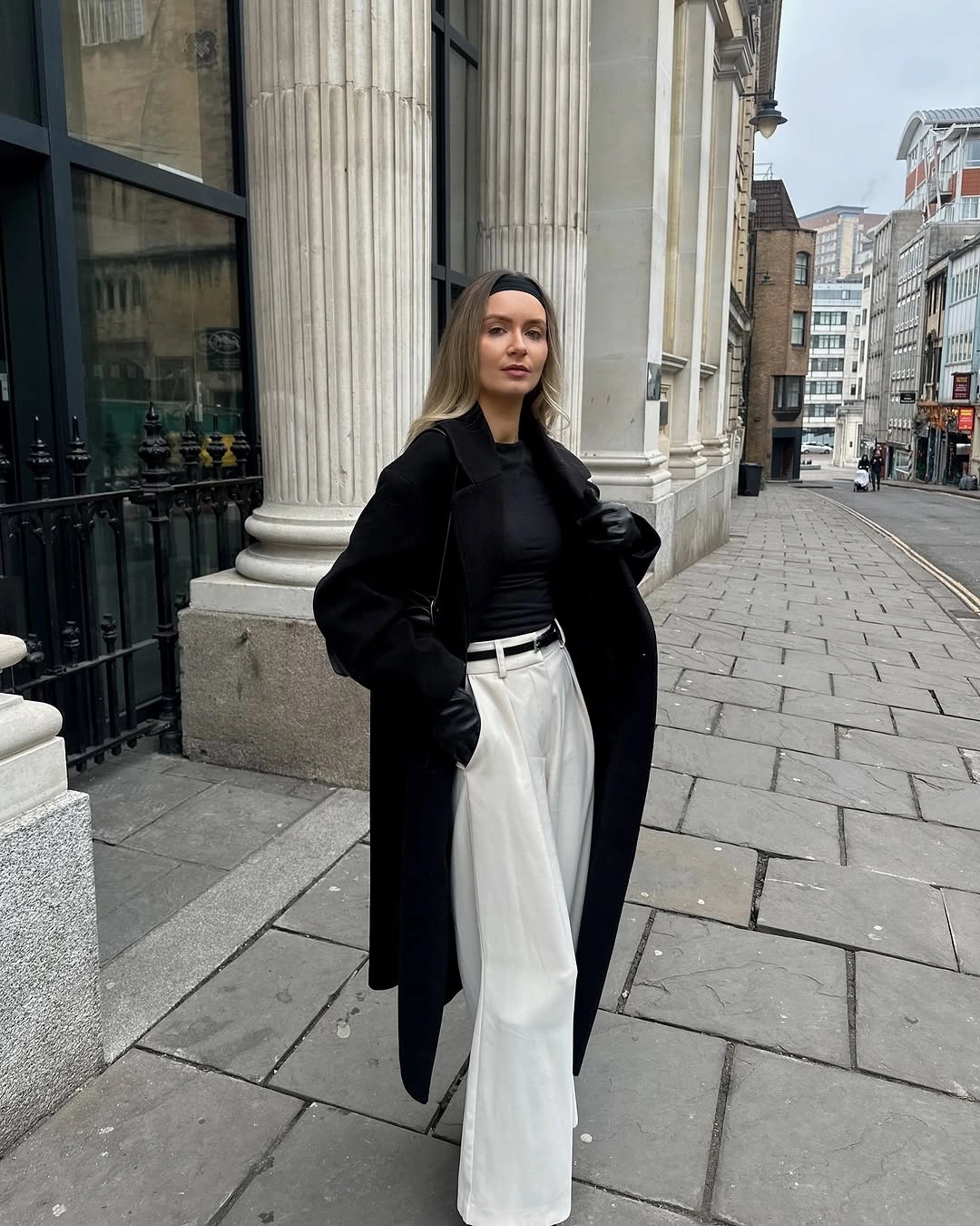 Black top with wide white trousers and black sunglasses in the city