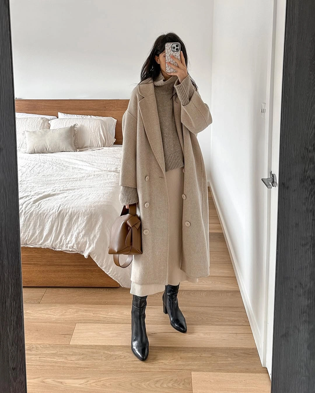 Long beige coat with beige-gray turtleneck, light trousers, and black boots
