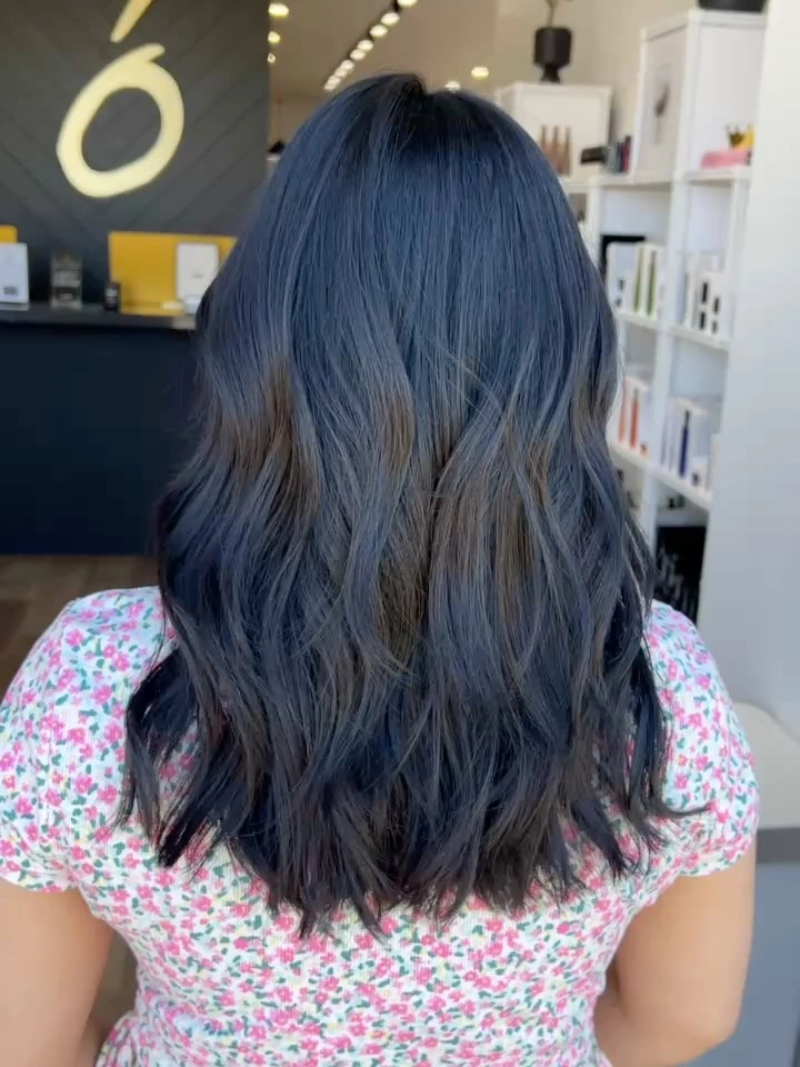 Back view of long blue-black wavy layered hair