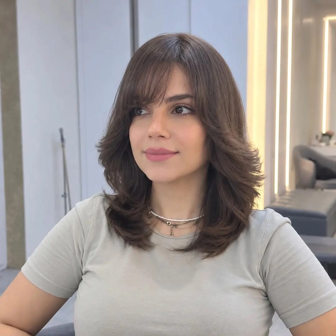Medium brown layered haircut with side-swept bangs