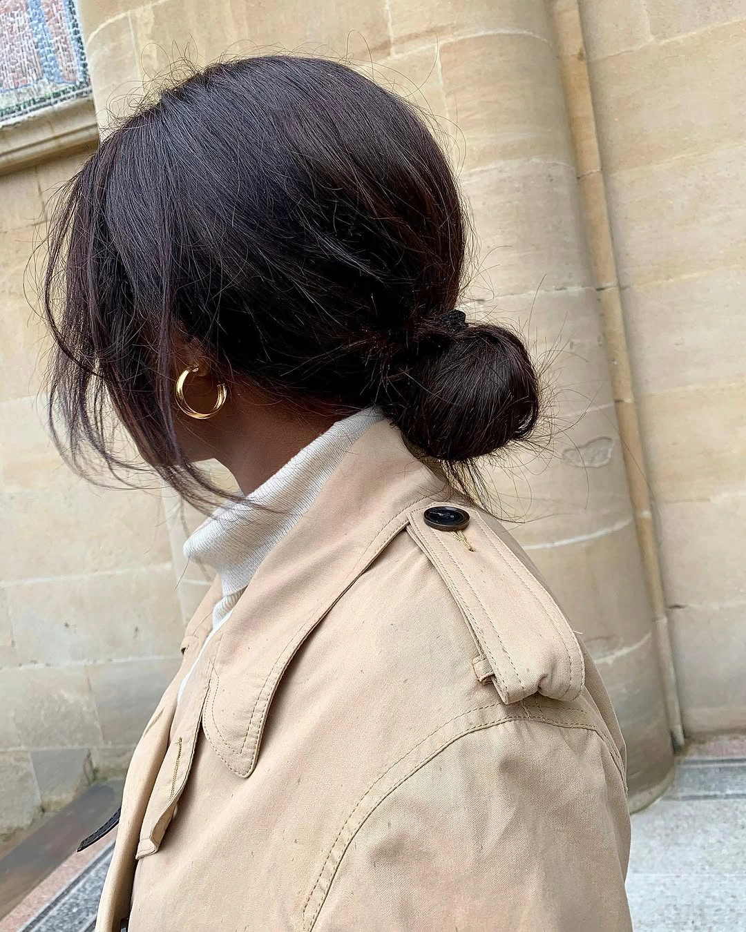 Low rounded dark bun with loose side strands
