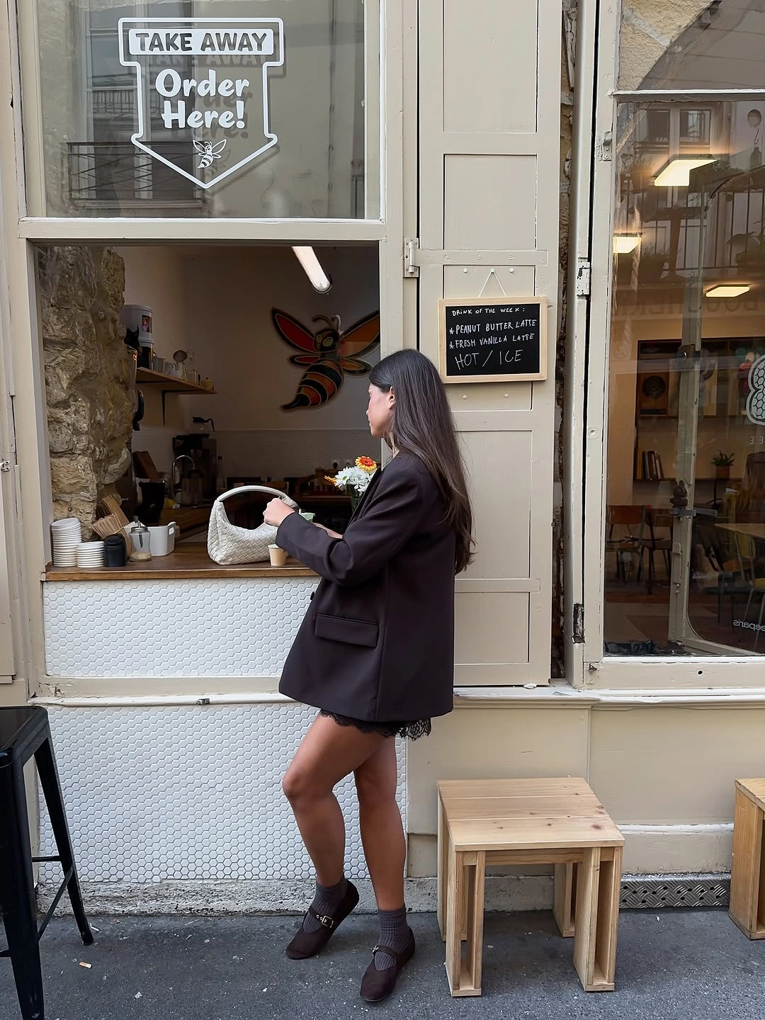 Black blazer, short skirt-like lower shape, and white woven-looking bag