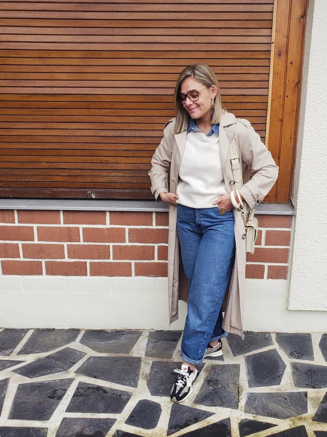 Cream coat, pale sweater, blue collar, jeans, and sneakers