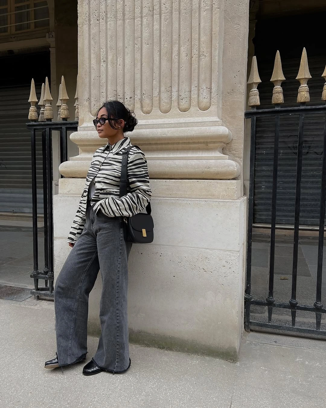 Black and cream striped top, gray wide jeans, black bag, and dark shoes