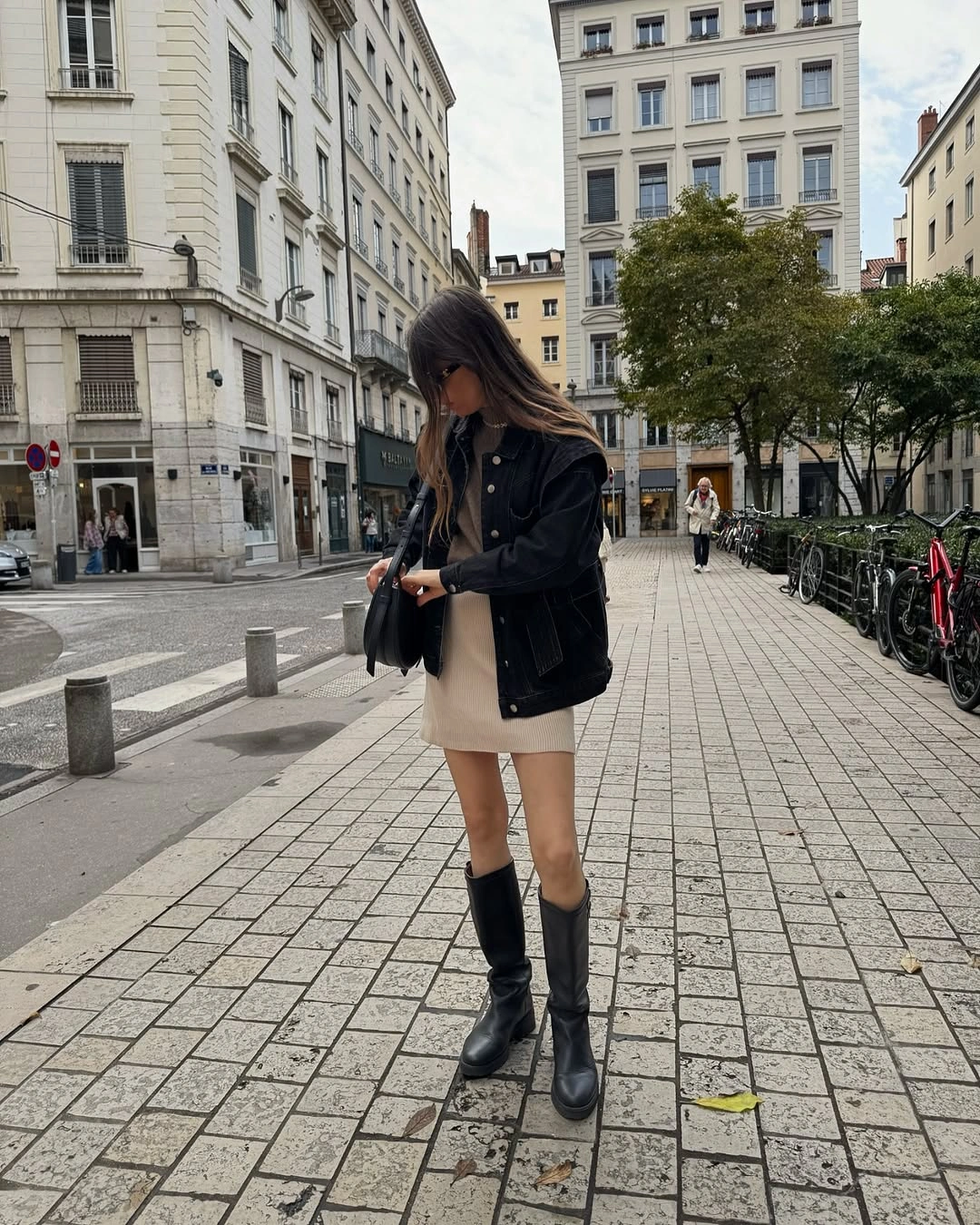 Dark jacket, cream mini skirt, knee-high black boots, and small bag