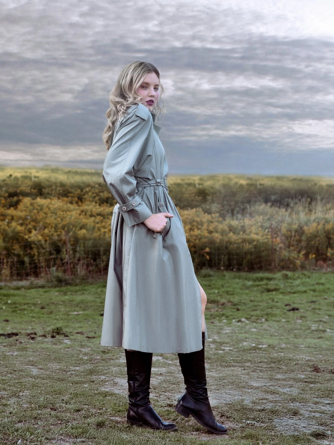 Pale blue belted coat with tall black boots outdoors