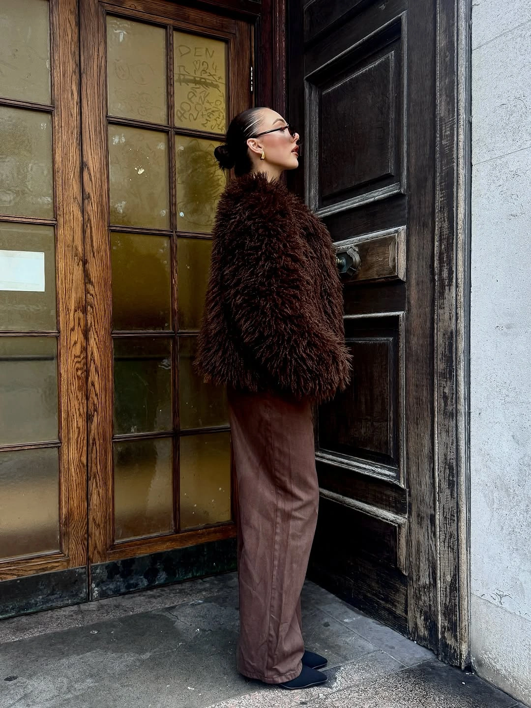 Dark fuzzy-looking jacket with brown trousers and blue shoes