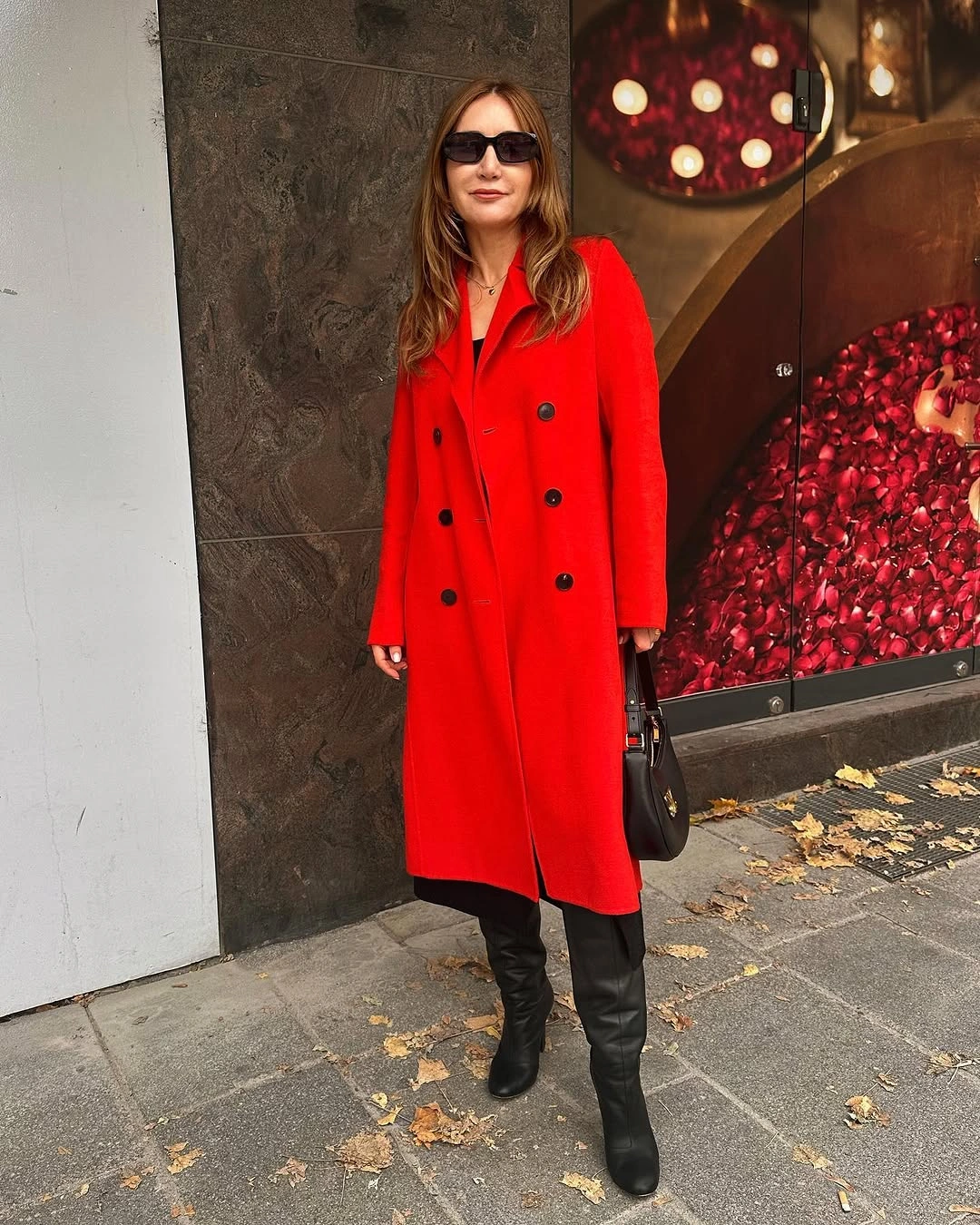Bright red double-breasted coat with black boots and handbag