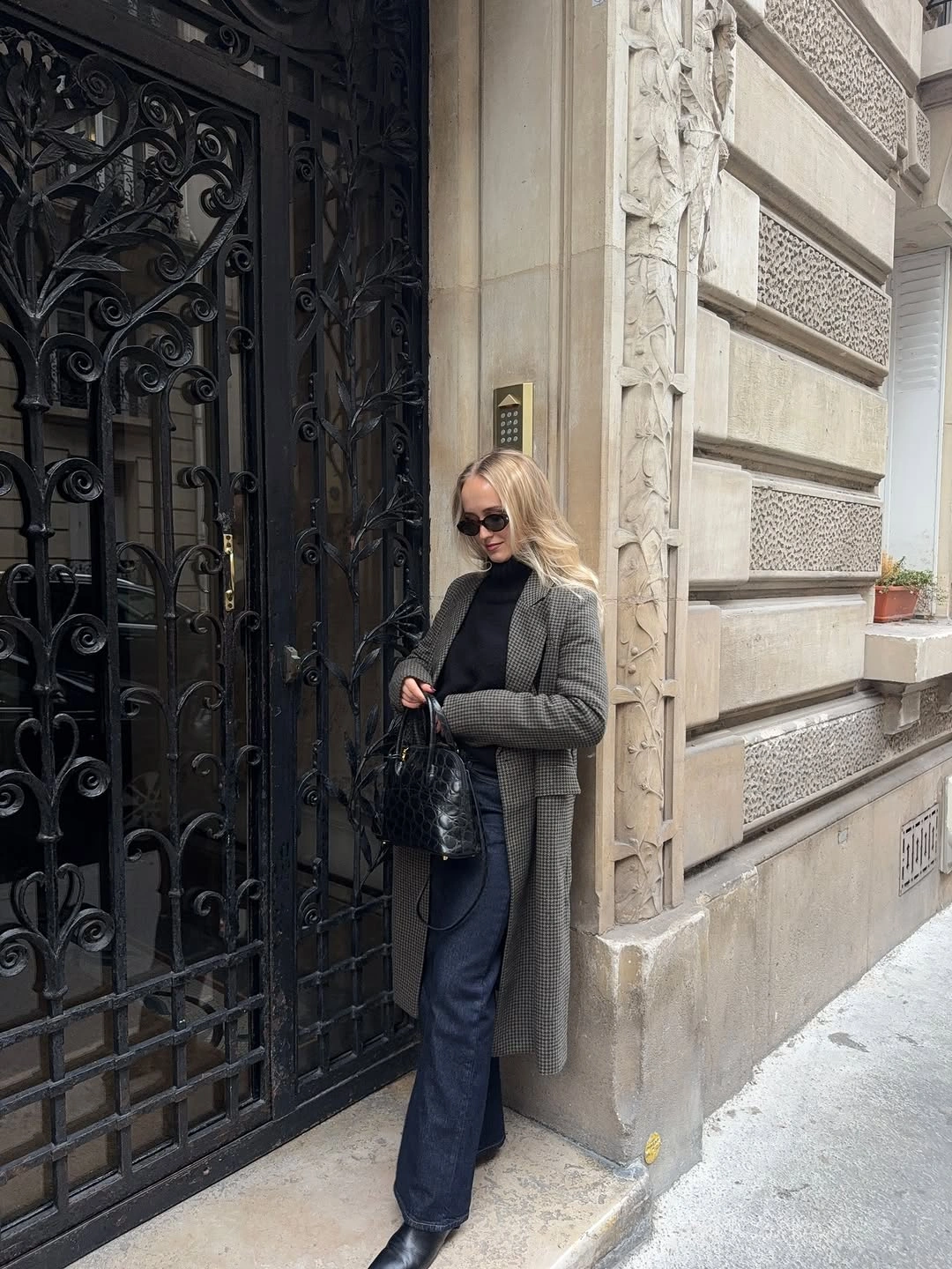 Cropped gray padded-looking jacket with dark trousers and black bag