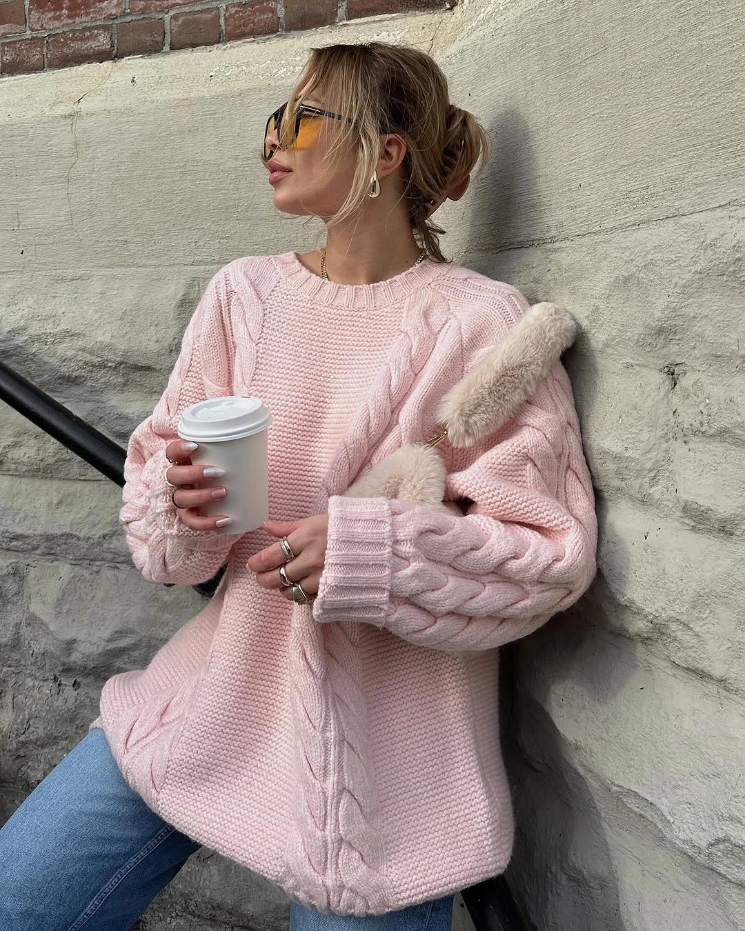 Pale pink oversized knit-looking sweater with jeans and light accessory