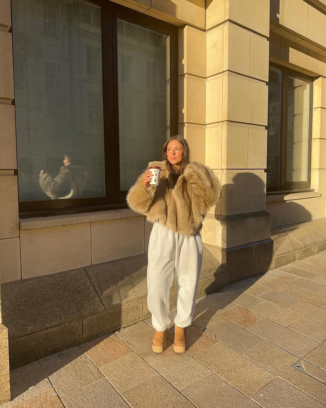 Beige fuzzy-looking jacket with white trousers and tan boots