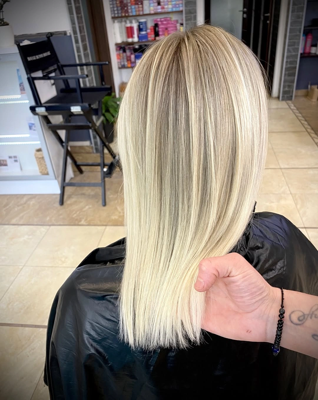 Shorter pale blonde hair with blunt-looking ends and root shadow