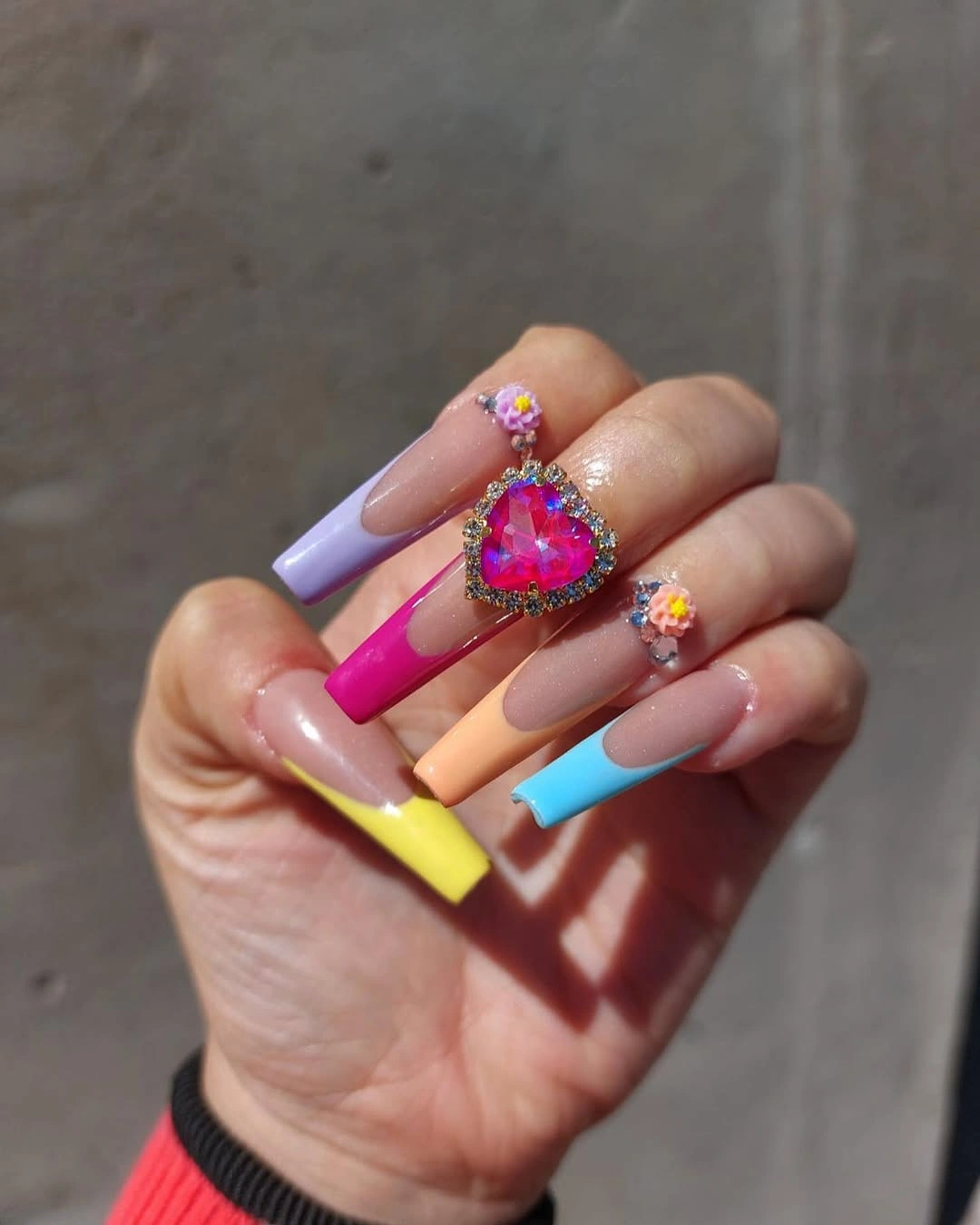 Long coffin-shaped nails with colorful tips and heart-shaped ornament