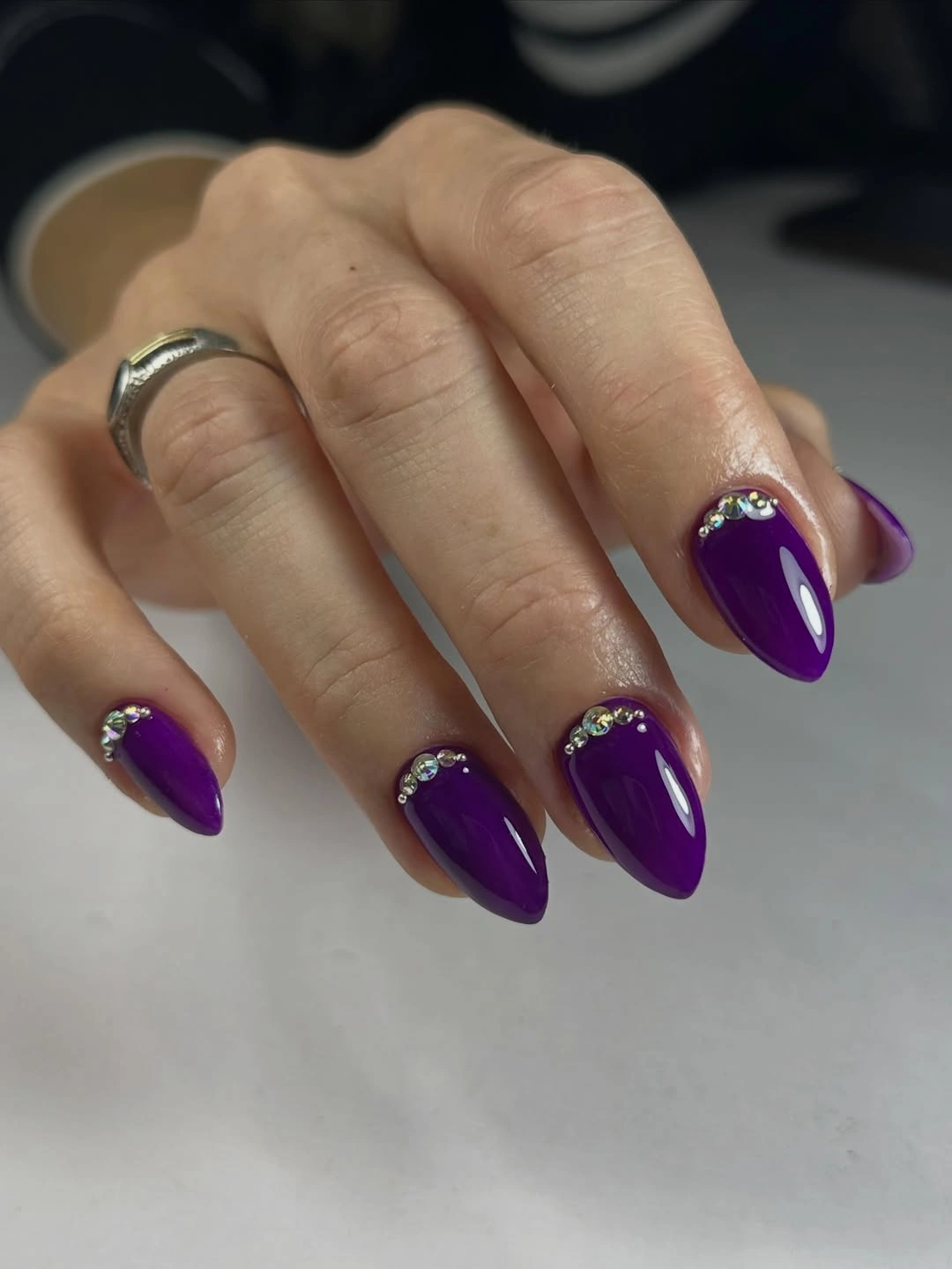 Saturated purple almond nails with cuticle rhinestone-like arcs