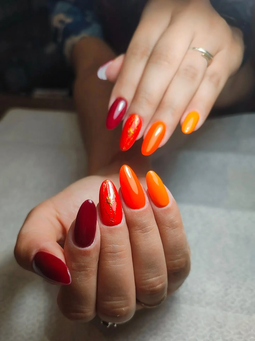 Long almond nails in burgundy, red, orange, and yellow-orange