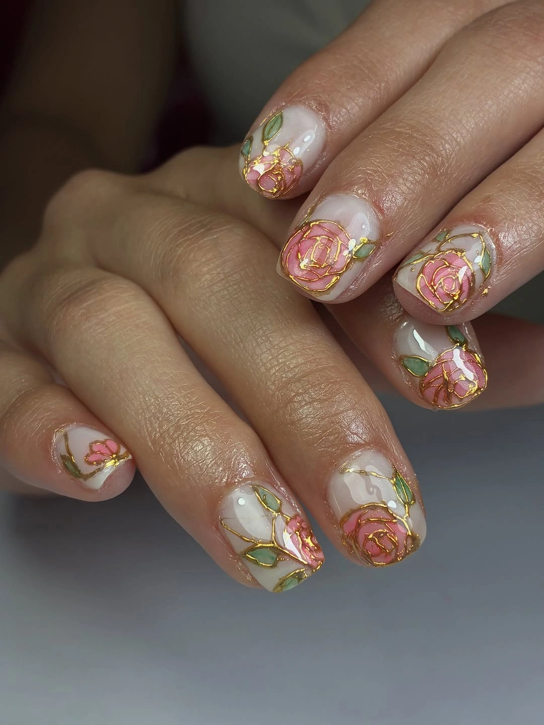 Short white nails with pink rose-like and green leaf-like details