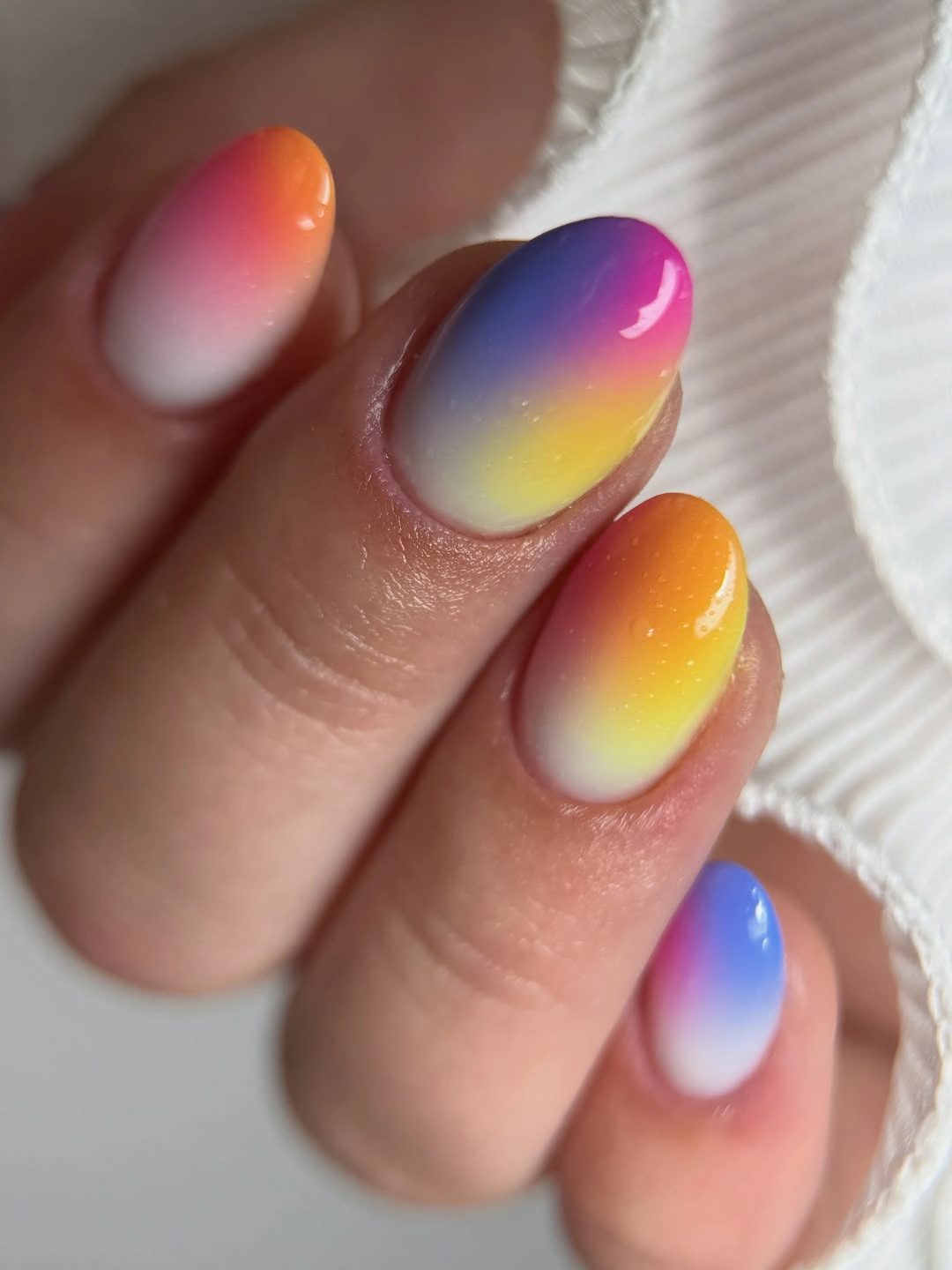 Oval nails with orange, yellow, pink, blue, and purple gradients