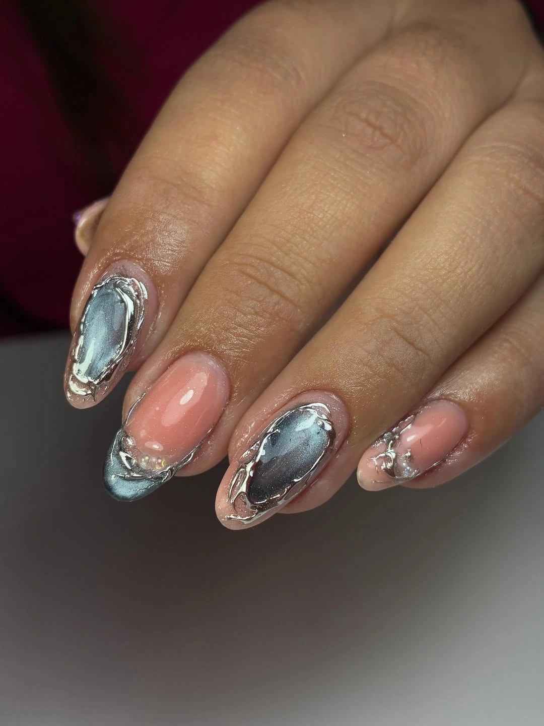 Nude pink almond nails with large metallic-looking silver areas